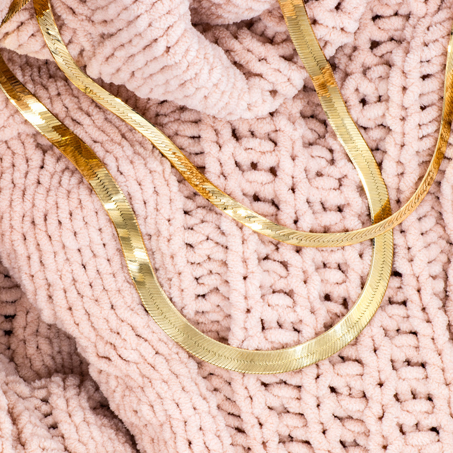 Gold necklaces on a pink textured fabric background
