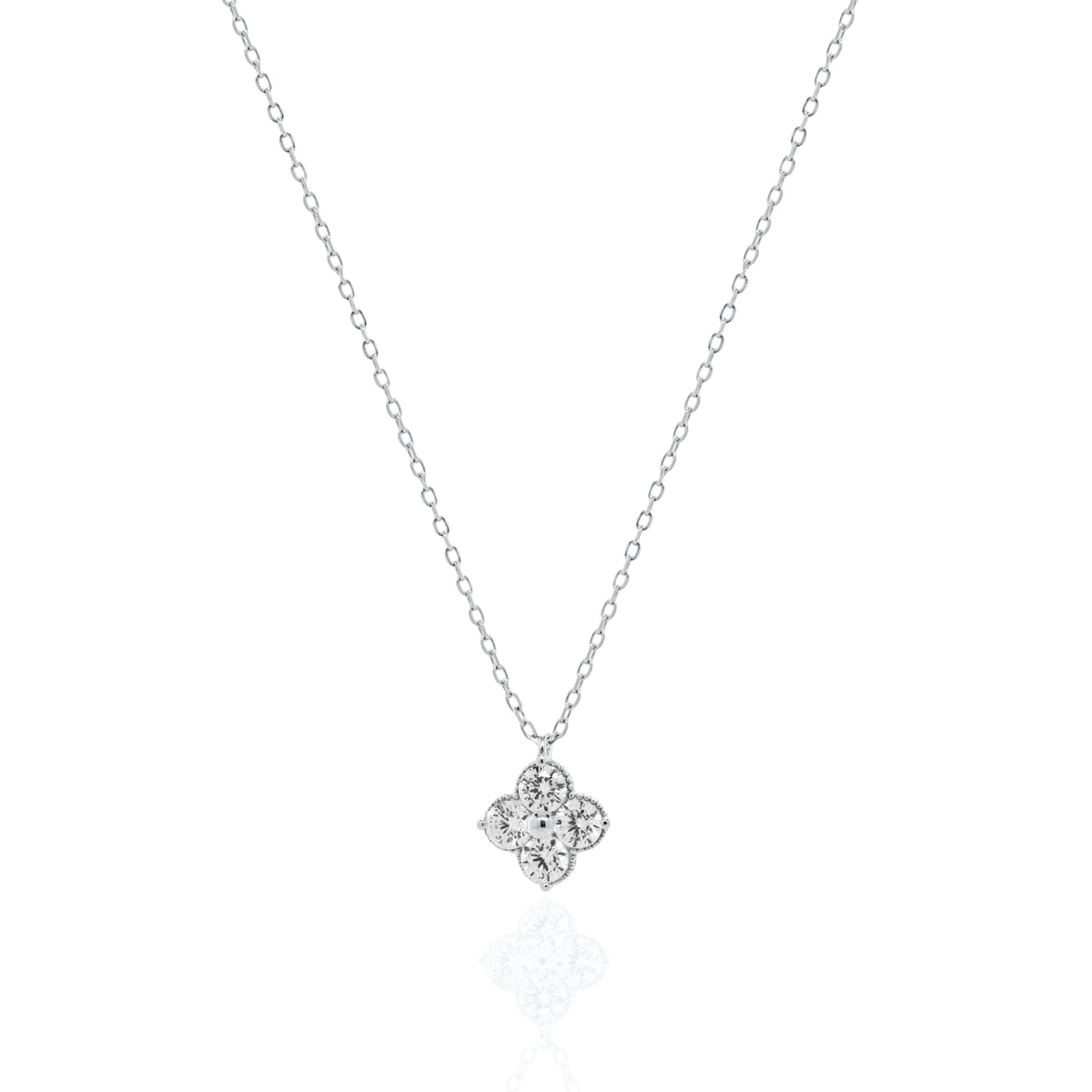 A delicate silver chain necklace with a small four-petal flower pendant set with clear stones, displayed on a clean white background with a soft reflection below.