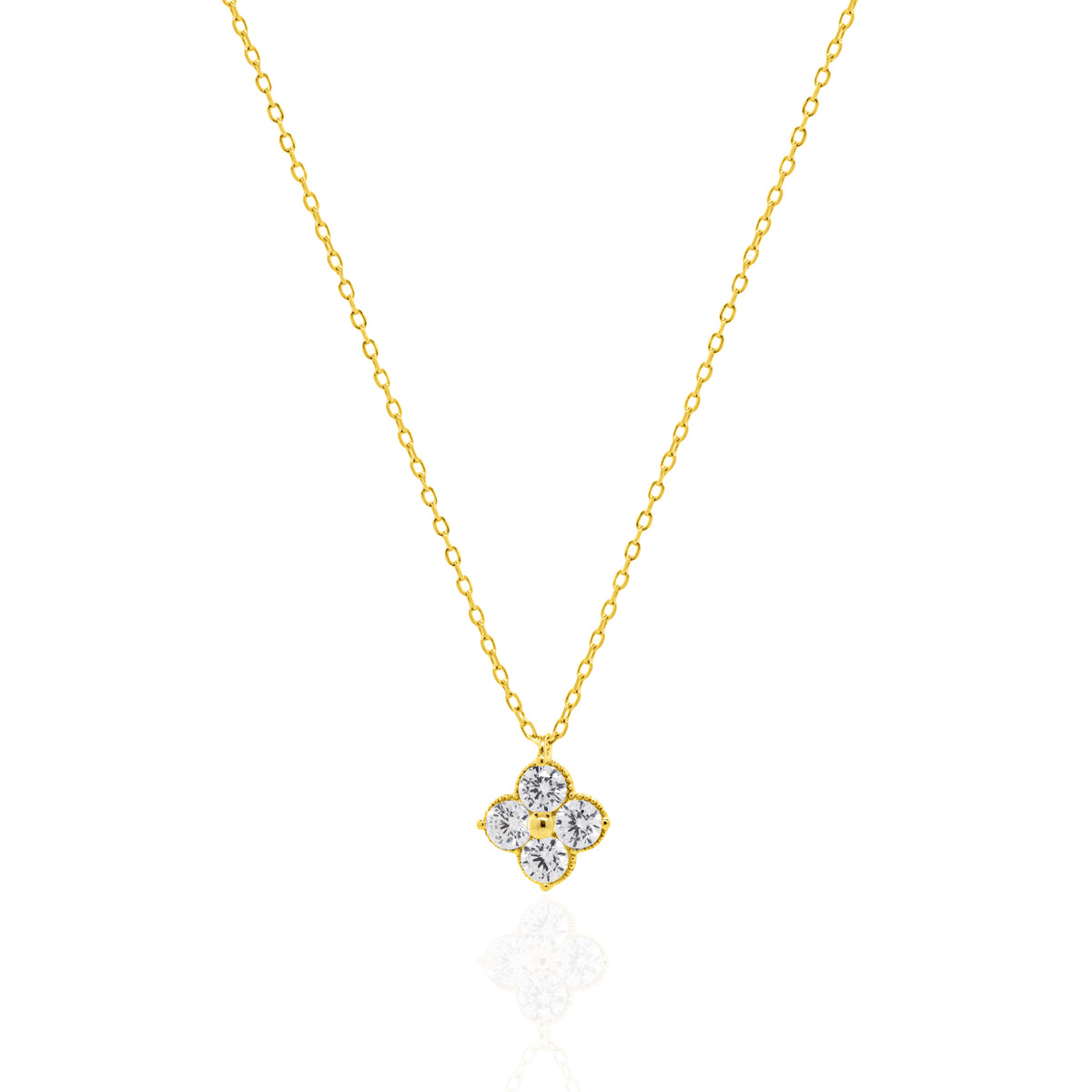 A delicate gold chain necklace with a small four-petal flower pendant set with clear gemstones, displayed on a clean white background with a soft reflection below.
