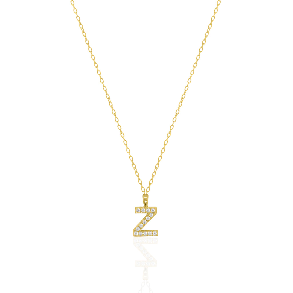 A goldtone initial necklace featuring a  letter pendant set with small clear stones, suspended from a delicate gold chain against a white background.