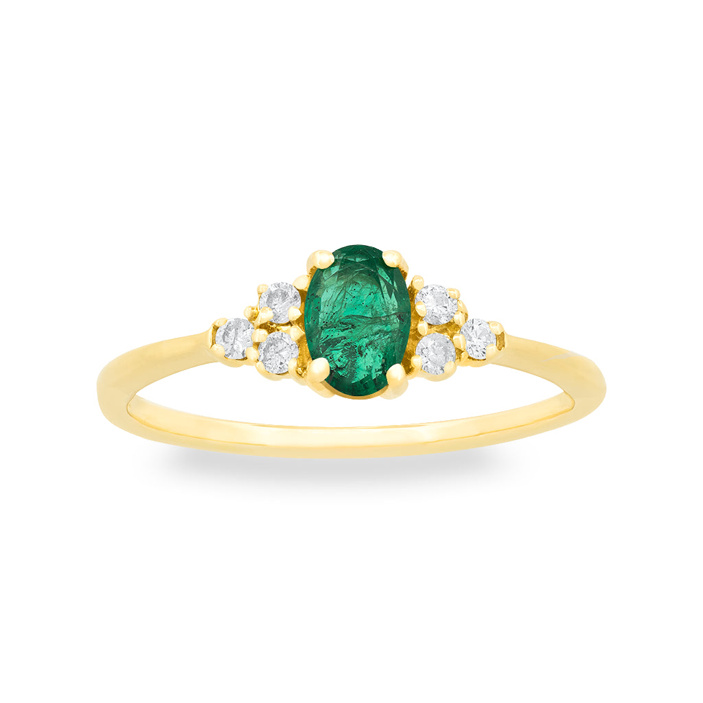 A yellow gold ring featuring an oval-cut green emerald center stone, flanked by small diamonds on each side, set against a plain white background.
