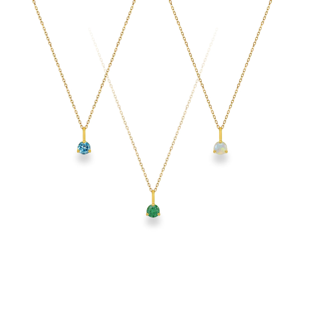 Three gold pendant necklaces on delicate chains, each featuring a small gemstone pendant in a claw setting: a light blue stone, a green stone, and an iridescent white stone, displayed on a clean white background.