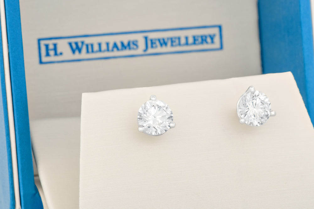 Diamond stud earrings in a blue box with 'H. Williams Jewellery' branding.