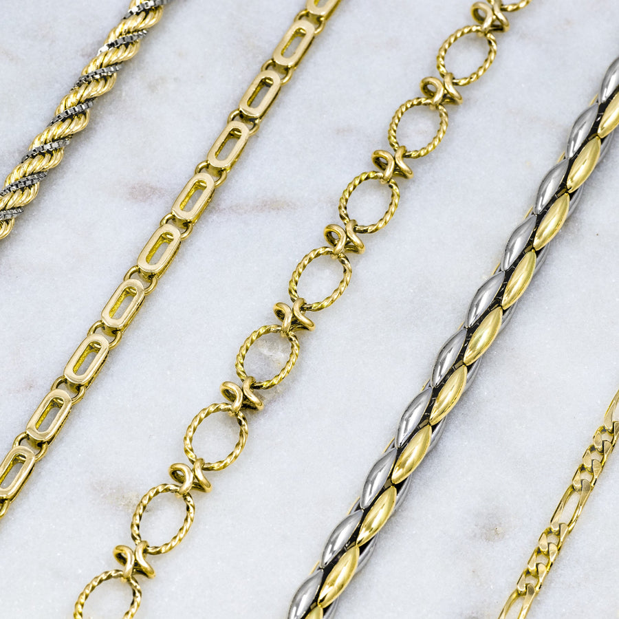 Gold and silver chain bracelets on a marble surface
